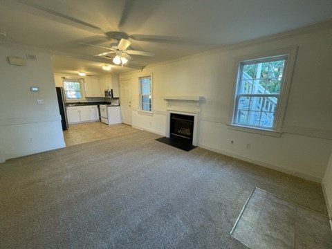 A living room with a fireplace and a ceiling fan.