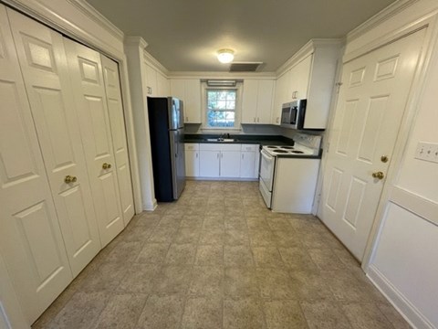 A kitchen with white cabinets and a black refrigerator.