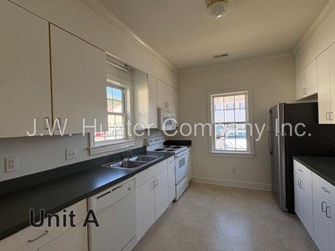 A kitchen with white cabinets and black countertops is labeled "Unit A.".