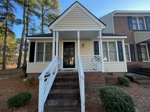 A house with a front porch and stairs leading up to the door.