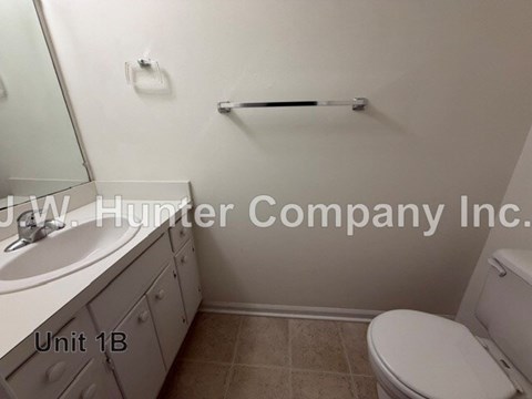 A bathroom with a toilet, sink, and towel bar.