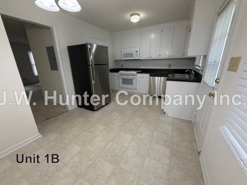 A kitchen with white cabinets and a black fridge is shown.