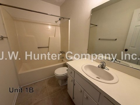 A bathroom with a toilet, sink, and mirror.