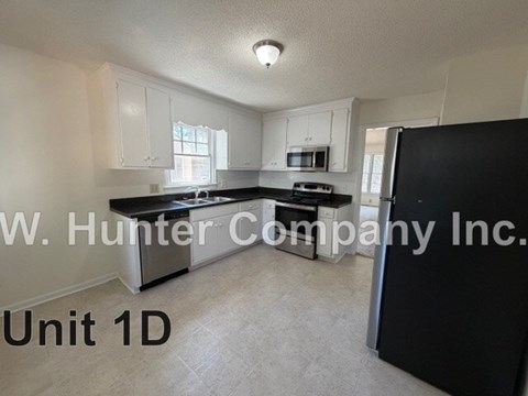 A kitchen with white cabinets and a black refrigerator.