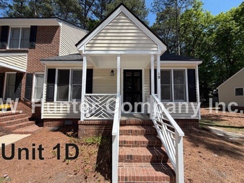 A house with a white front porch and a sign that says "Unit 1D" in front of it.