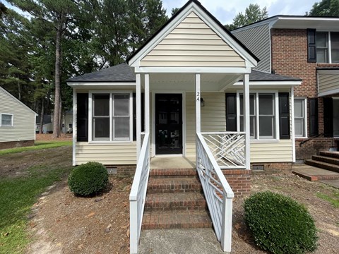 A small house with a front porch and stairs leading up to the door.