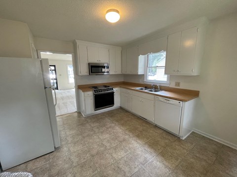A kitchen with white cabinets and a tiled floor.