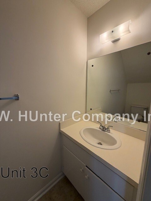 A bathroom with a sink and mirror in white.