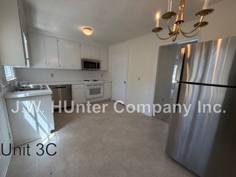 A kitchen with white cabinets and a stainless steel refrigerator.