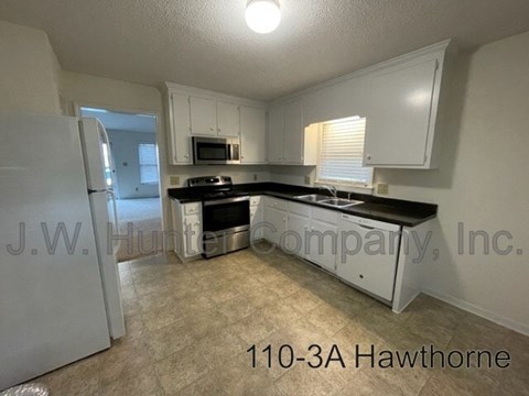 A kitchen with white cabinets and black countertops.