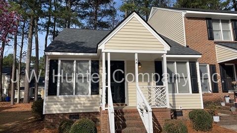 A house with a white porch and a brick wall.