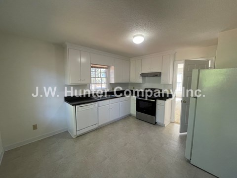 A spacious kitchen with white cabinets and a black countertop.
