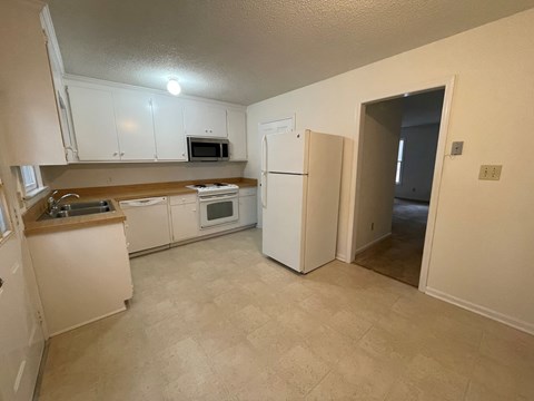 A kitchen with white cabinets and appliances.