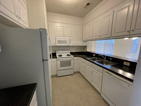 A kitchen with white cabinets and appliances.