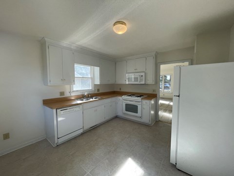 A kitchen with white appliances and cabinets.