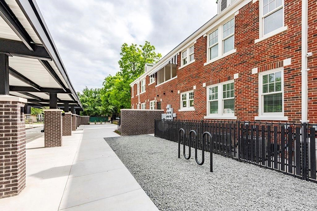 a large brick building with a sidewalk and a black fence