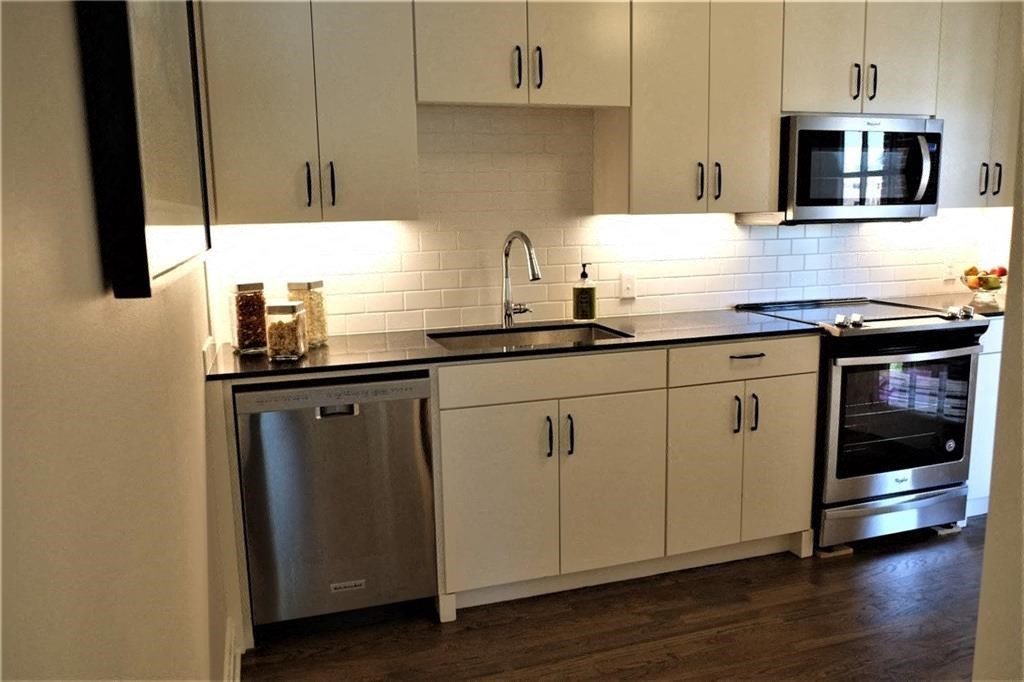 a kitchen with white cabinets and a sink and a microwave