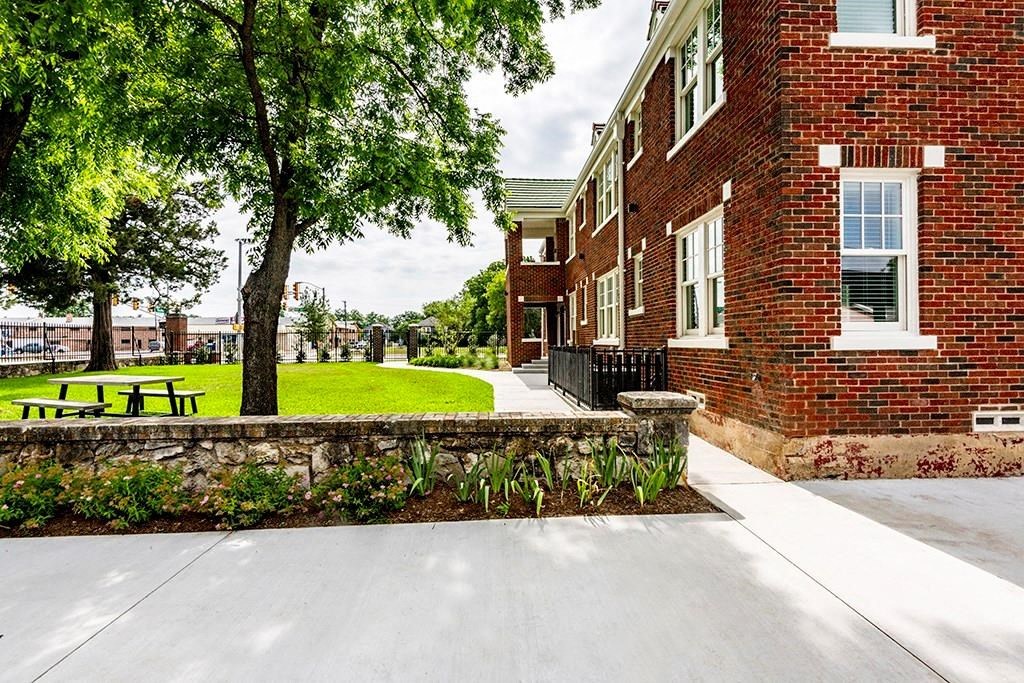 the front of a brick building with a lawn and trees