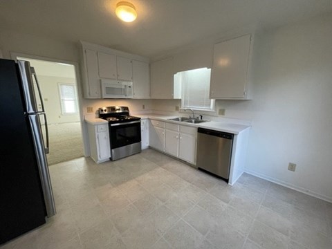A kitchen with white cabinets and a black refrigerator.