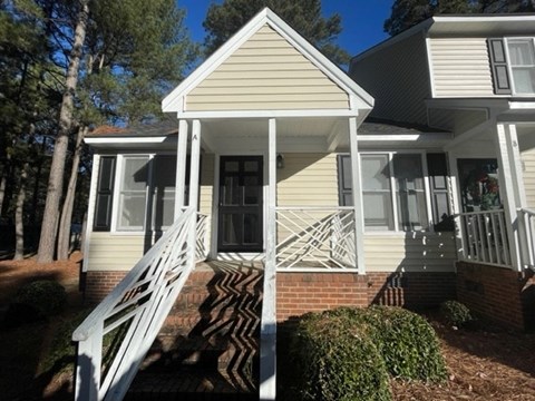 A house with a white porch and stairs leading to the front door.