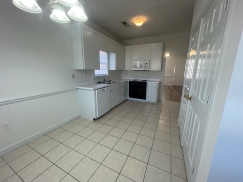 A kitchen with white cabinets and a white refrigerator.