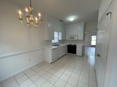 A kitchen with white cabinets and a chandelier.
