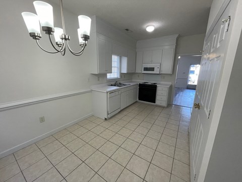 A kitchen with white cabinets and a black dishwasher.