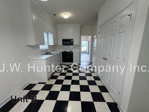 A black and white checkered floor in a white kitchen.