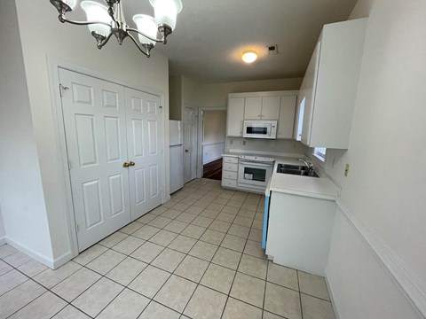 A kitchen with white cabinets and a white refrigerator.