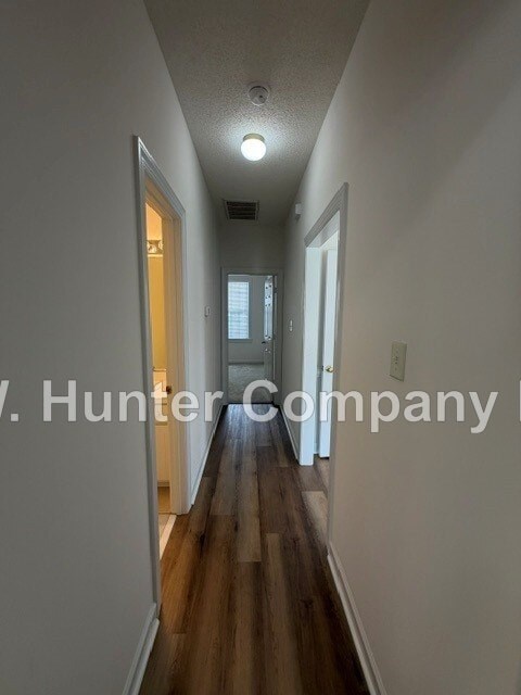 A long hallway with a light on the ceiling and a door on the right.