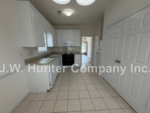 A kitchen with white cabinets and a tiled floor.