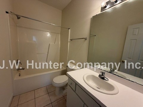 A white sink in a bathroom with a white toilet and a glass shower door.