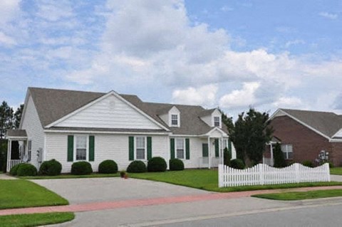A white house with a black roof and a white picket fence.