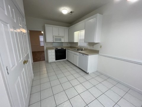 A kitchen with white cabinets and appliances.