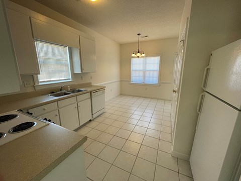 A kitchen with white appliances and white cabinets.