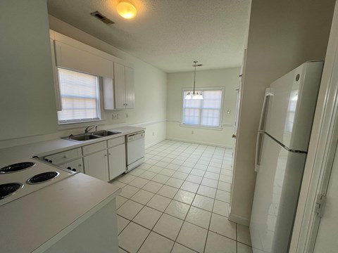 A kitchen with white appliances and a white tile floor.
