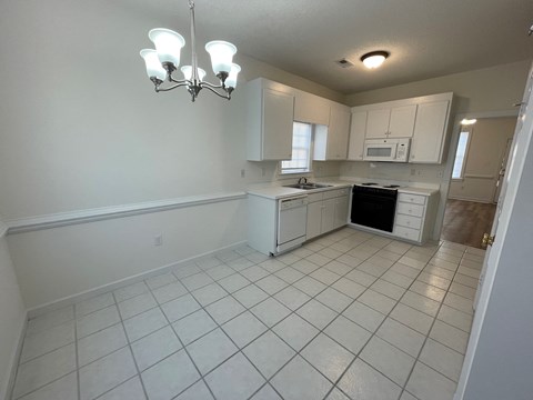 A kitchen with white cabinets and appliances.