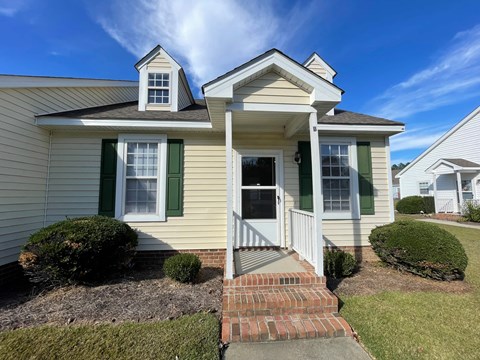 A house with a white door and green shutters.