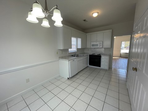 A kitchen with white cabinets and a white fridge.