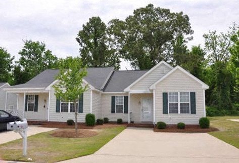 a white house with green shutters and a driveway