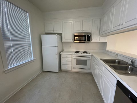 A kitchen with white appliances and cabinets.