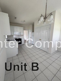 A kitchen with white cabinets and a white door.