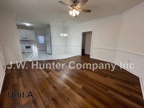 A spacious room with wooden flooring and a ceiling fan.