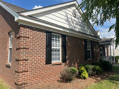 A red brick house with a white roof and black shutters.