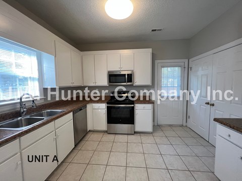 A kitchen with white cabinets and a brown countertop.