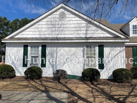 A white house with green shutters and a brick chimney.