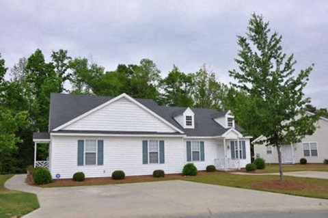 a white house with a gray roof and a driveway