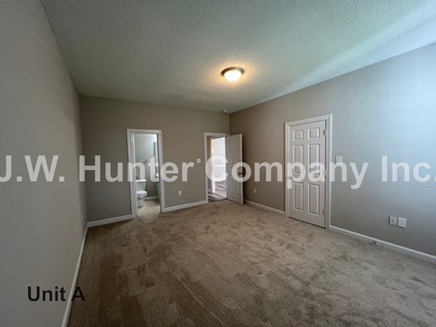 A room with carpet flooring and a textured wallpaper that reads "J.W. Hunter Company Inc.".