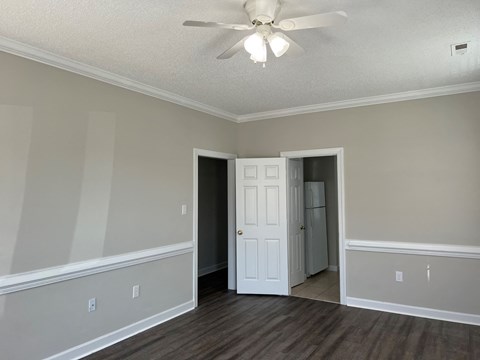 an empty living room with a ceiling fan and a door to a closet