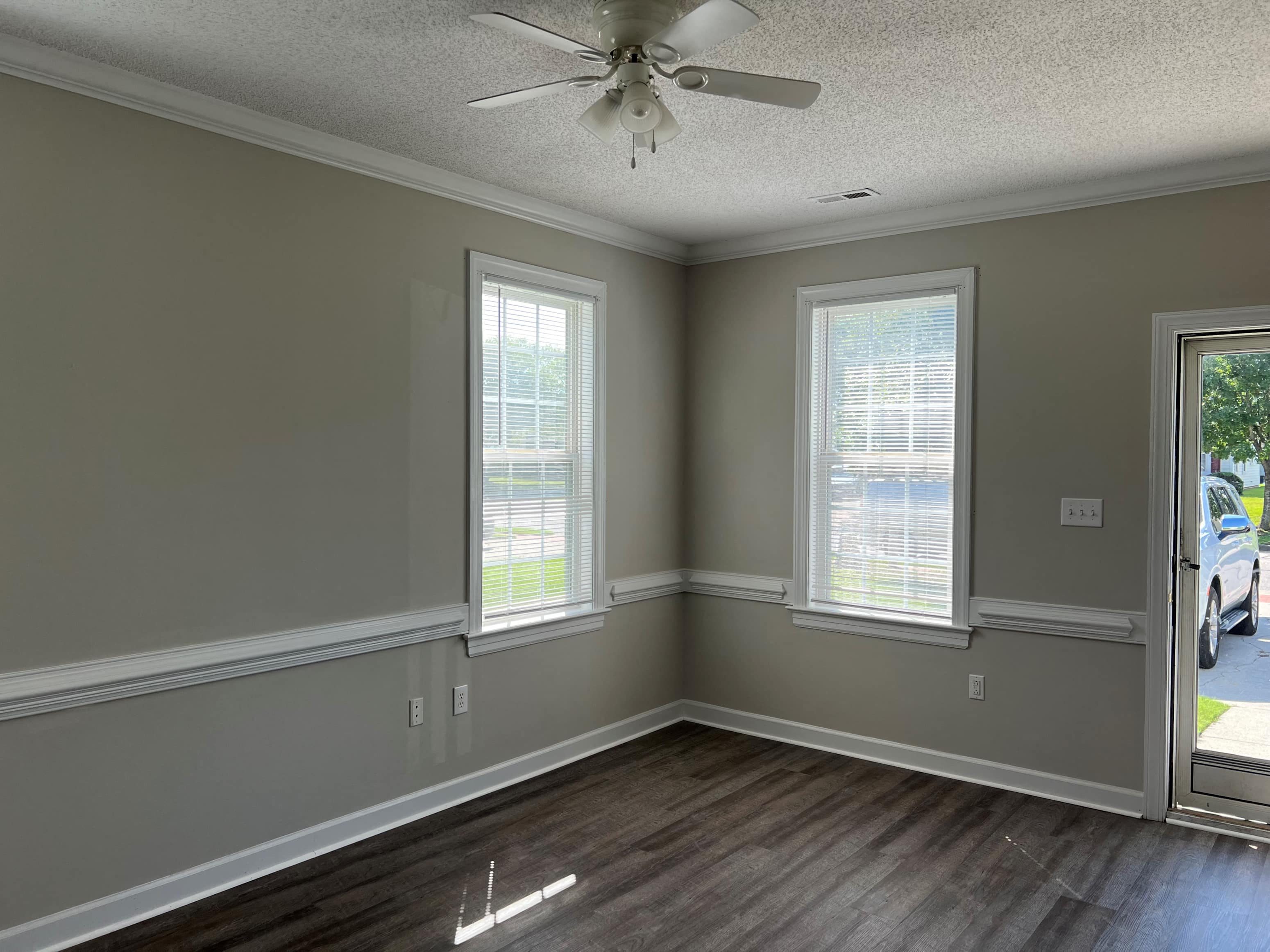 an empty living room with a ceiling fan and two windows